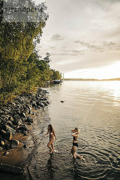 Hohe Winkel Ansicht der weiblichen Freunde genießen Urlaub am See bei Sonnenuntergang