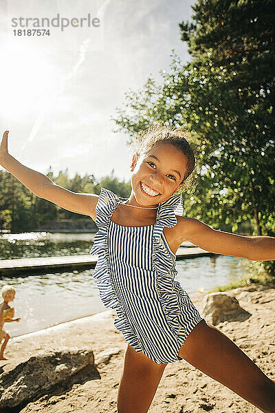 Porträt eines glücklichen Mädchens mit ausgestreckten Armen  das einen sonnigen Tag im Urlaub genießt