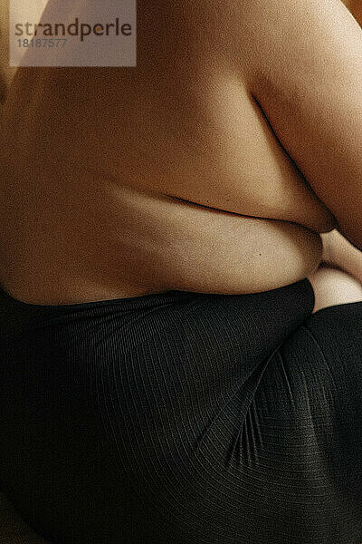 Hemdlose Frau mit Dehnungsstreifen in schwarzer Unterwäsche