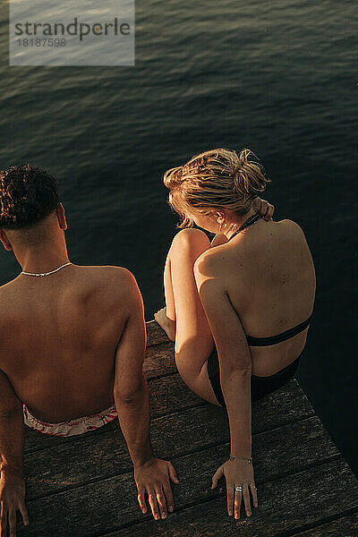 Hohe Winkel Ansicht der Frau sitzt auf Steg mit männlichen Freund durch See