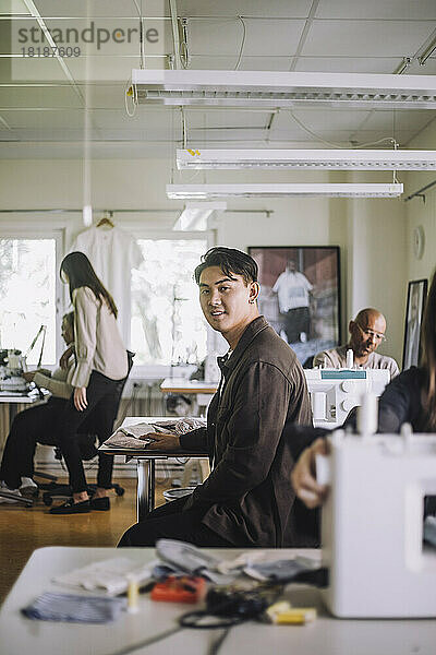 Seitenansicht eines männlichen Designers  der in einer Werkstatt sitzt