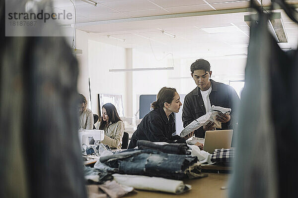 Modedesigner halten Pakete  während sie in einem Workshop zusammenarbeiten