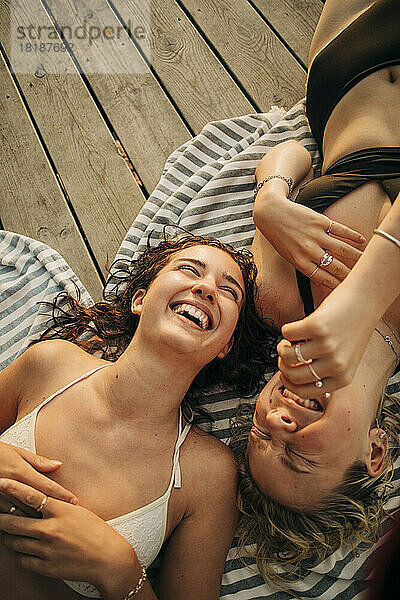 Hohe Winkel Ansicht der glücklichen weiblichen Freunde genießen Urlaub  während auf Steg liegen