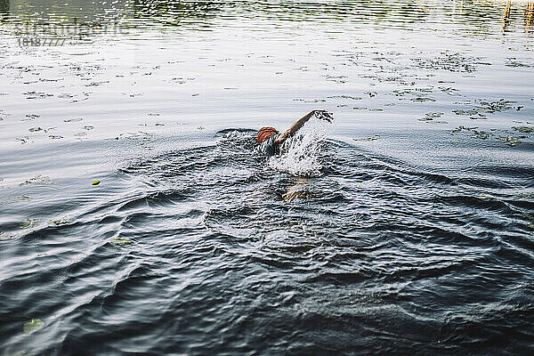 Älterer Mann spritzt im Wasser  während er Freistilschwimmen im See übt
