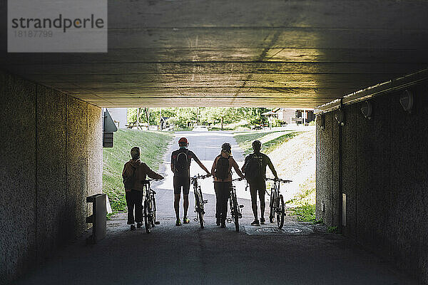 Männliche und weibliche Freunde fahren mit Fahrrädern durch eine Unterführung