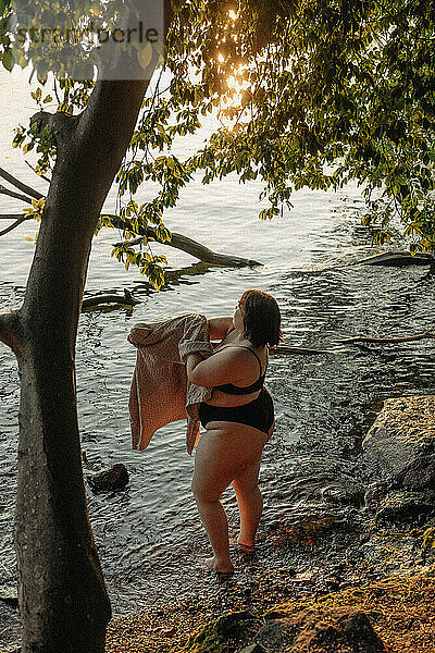 Hohe Winkel Ansicht der jungen Frau mit Handtuch stehen im Wasser durch Baum