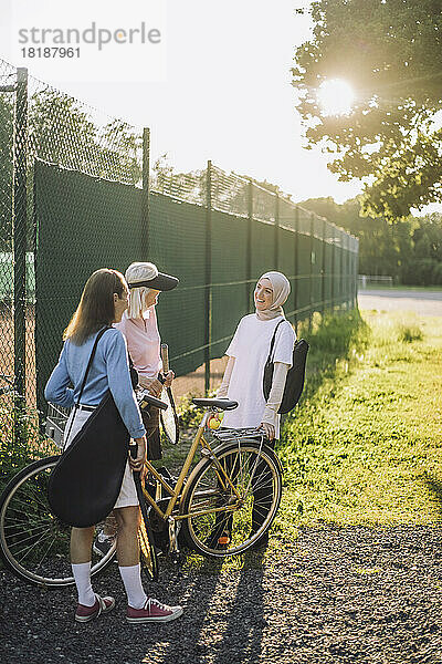 Ältere Frauen mit Fahrrad im Gespräch mit einer Freundin an einem sonnigen Tag