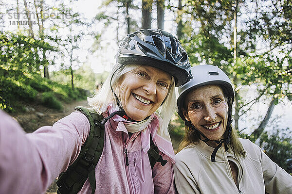 Porträt einer glücklichen älteren Frau  die ein Selfie macht und einen Fahrradhelm trägt