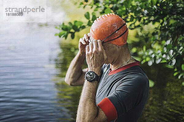 Älterer Mann passt Schwimmbrille im See an