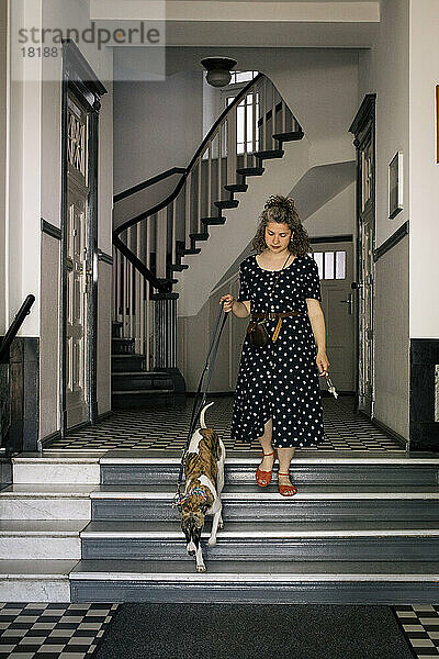 Frau geht mit Hund eine Treppe hinunter