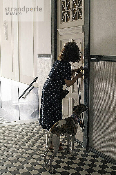 Frau verriegelt Haustür  während sie mit Hund steht
