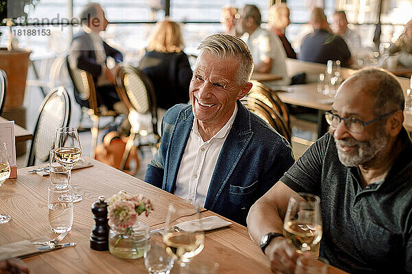 Glücklicher älterer Mann sitzt mit einem männlichen Freund im Restaurant