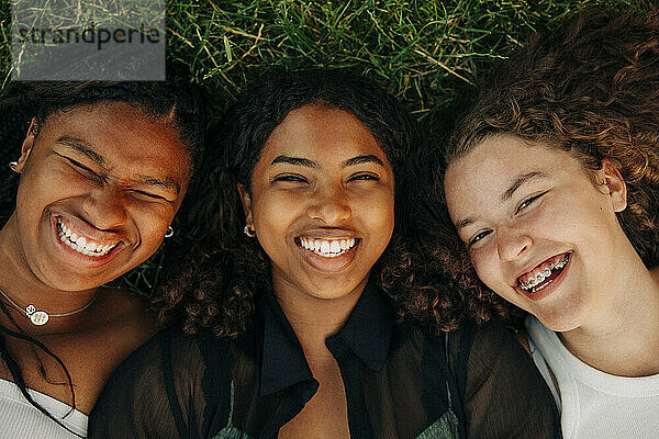 Porträt von glücklichen Teenager-Mädchen  die lachend im Gras liegen