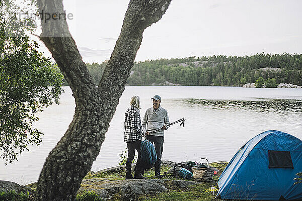 Älterer Mann im Gespräch mit einem Freund beim Camping am See