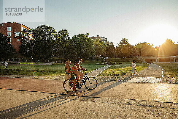 Teenager-Mädchen sitzt mit Freund Fahrrad fahren im Park bei Sonnenuntergang