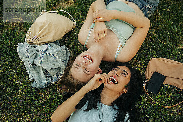 Fröhliche Teenager-Mädchen liegen zusammen im Park