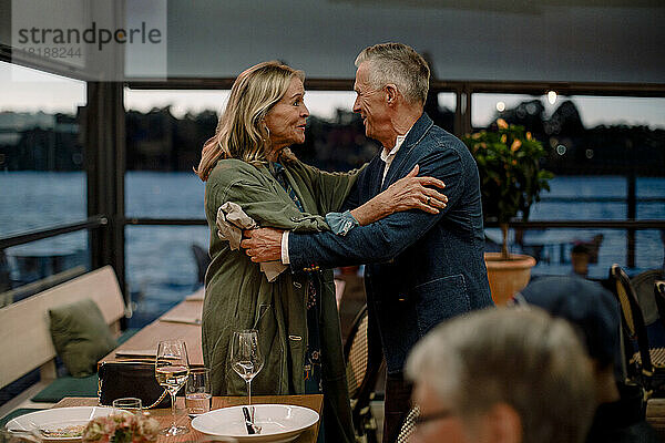 Lächelndes älteres Paar  das sich im Restaurant begrüßt