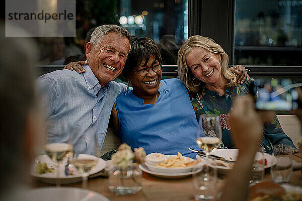 Glückliche männliche und weibliche ältere Freunde genießen im Restaurant während der Nacht