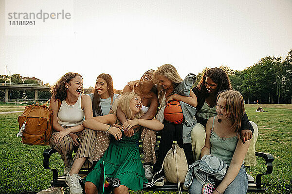 Fröhliche multirassische Teenager-Mädchen  die auf einer Bank im Park sitzen und Spaß haben