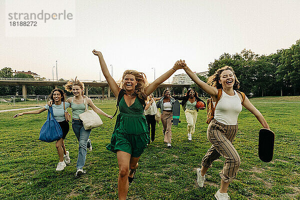 Unbeschwerte Teenager-Mädchen in voller Länge  die zusammen im Park laufen