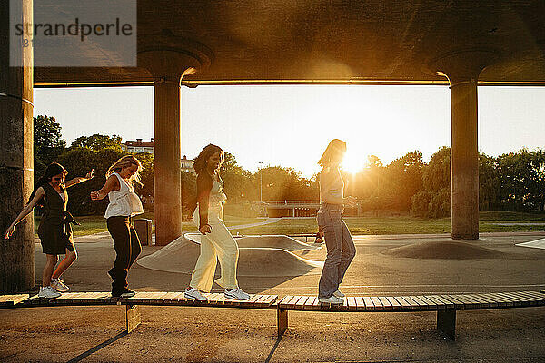 In voller Länge von Teenager-Mädchen zu Fuß auf der Bank unter der Brücke bei Sonnenuntergang