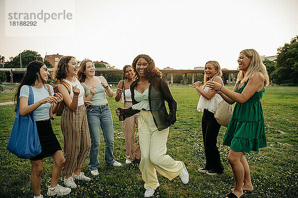 Teenager-Mädchen jubelnden Freund tanzen im Park bei Sonnenuntergang