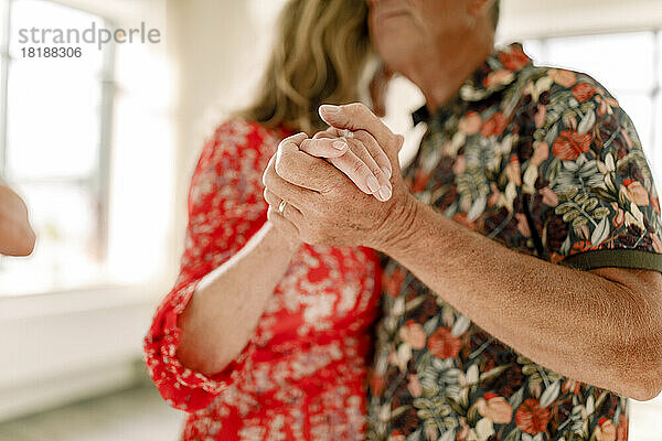 Älteres Paar hält sich an den Händen und tanzt zusammen im Unterricht