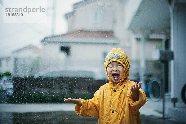 Japanisches Kind  das an einem regnerischen Tag draußen spielt
