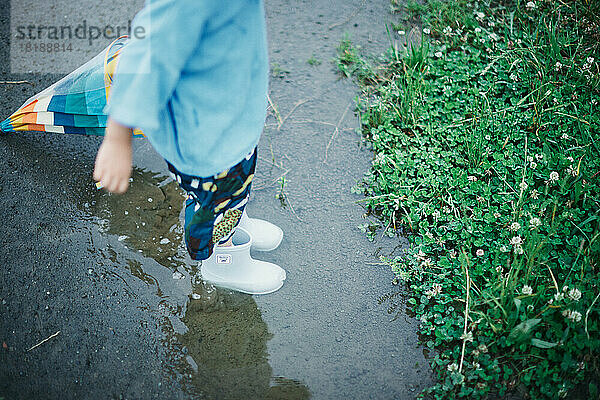 Japanisches Kind  das an einem regnerischen Tag draußen spielt