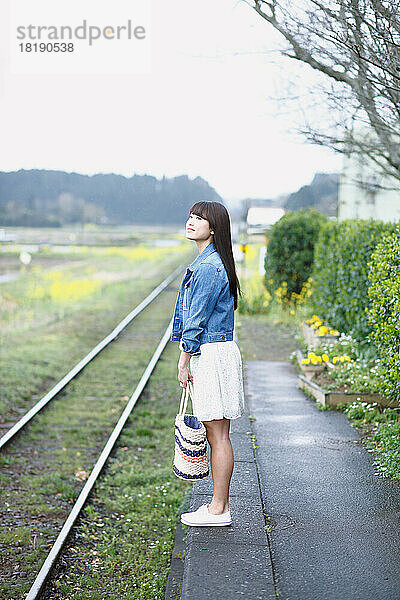 Junge Japanerin wartet am Bahnsteig auf einen Zug