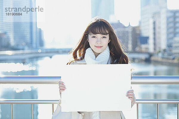 Japanische Frau im Winter hält ein Whiteboard