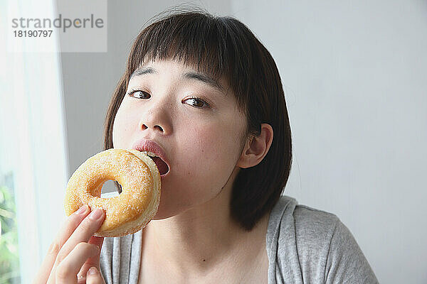 Junge Japanerin isst einen Donut