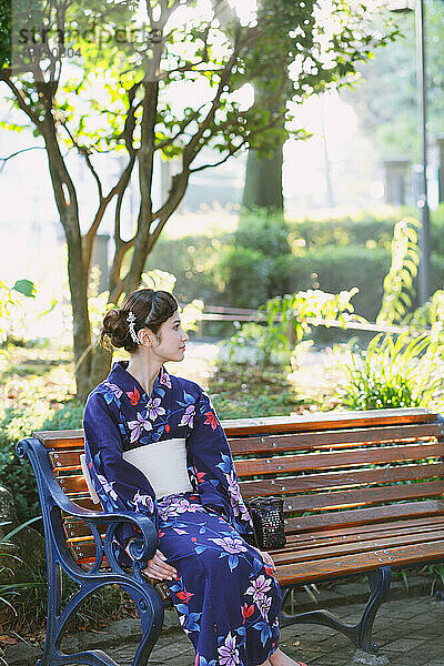 Japanerin in einem Yukata sitzt auf einer Bank