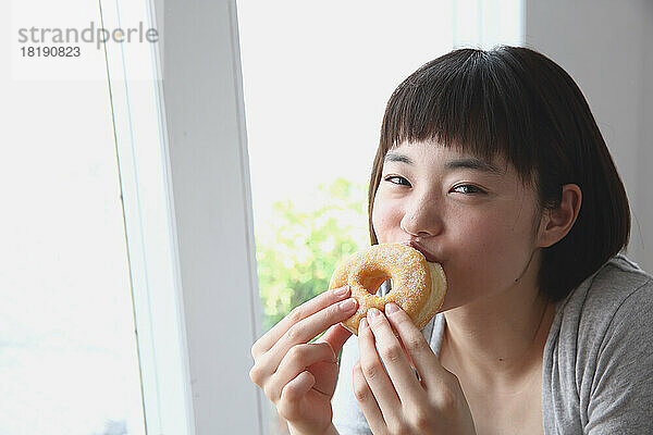 Junge Japanerin isst einen Donut