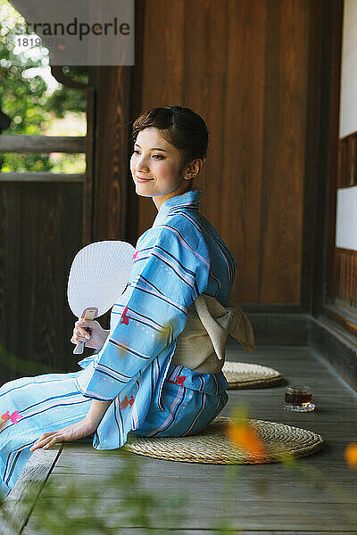 Japanerin in Yukata kühlt sich auf der Veranda ab