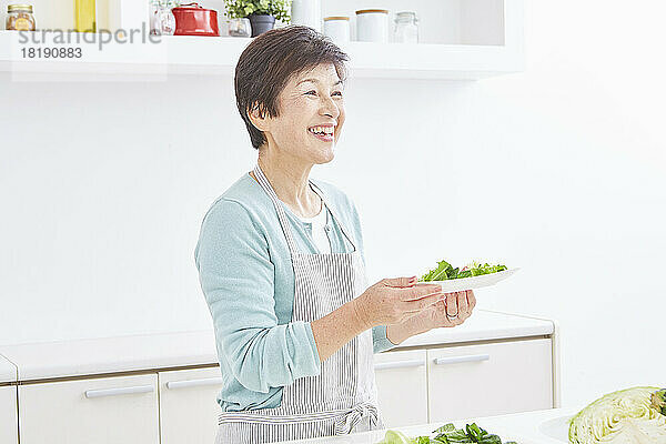 Ältere japanische Frau trägt eine Portion Salat