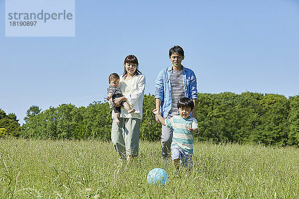 Japanische Eltern wachen über ein Kind  das Ball spielt