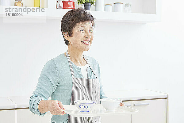 Japanische Seniorin trägt Portionen Reis