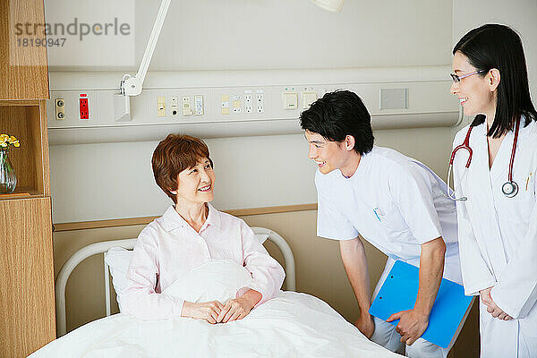Ältere Frau wird von einem Arzt und einer Krankenschwester in einem Krankenzimmer untersucht