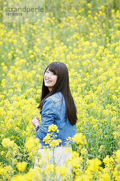 Eine junge Frau blickt zurück in ein Blumenfeld