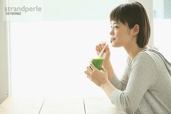 Junge Japanerin trinkt grünen Smoothie