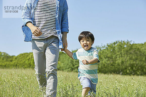 Japanische Eltern und Kinder halten sich an den Händen und laufen