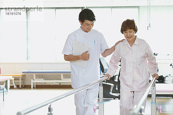 Ältere japanische Frau und junger Krankenpfleger in der Reha-Einrichtung