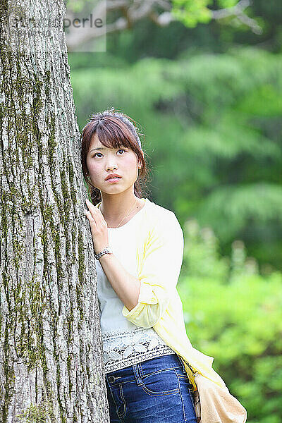 Japanerin lehnt an einem Baum