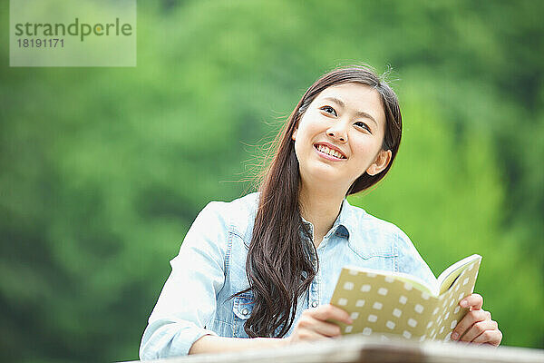 Japanerin liest im Freien ein Buch