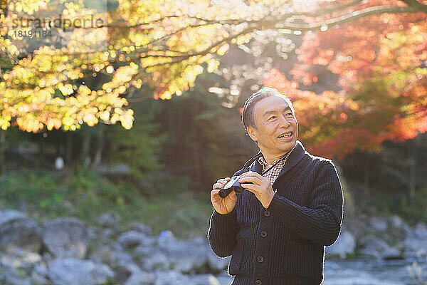 Älterer japanischer Mann  der in der Herbstlaubsaison unterwegs ist