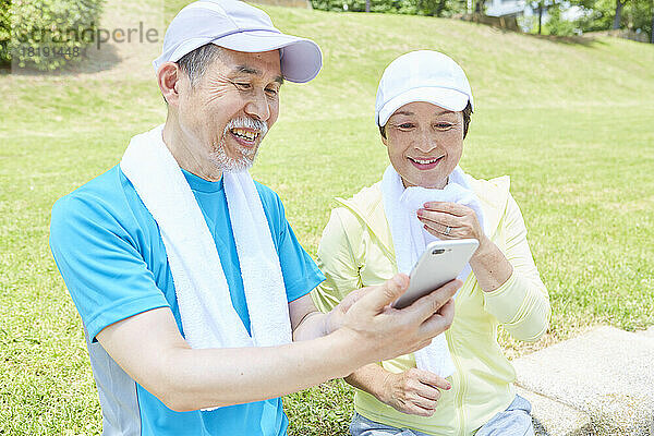 Japanisches älteres Paar schaut aufs Handy