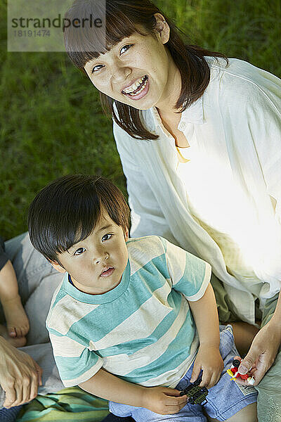 Japanische Eltern und Kinder entspannen sich auf dem Rasen