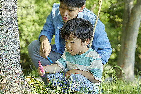 Japanische Eltern und Kinder sammeln Insekten