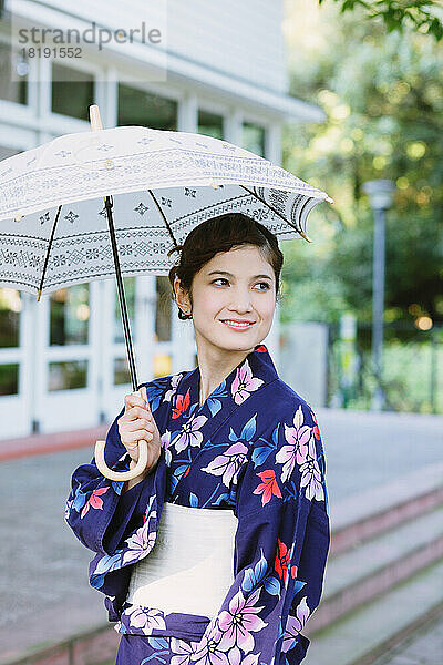 Japanische Frau in einem Yukata  der einen Sonnenschirm hält